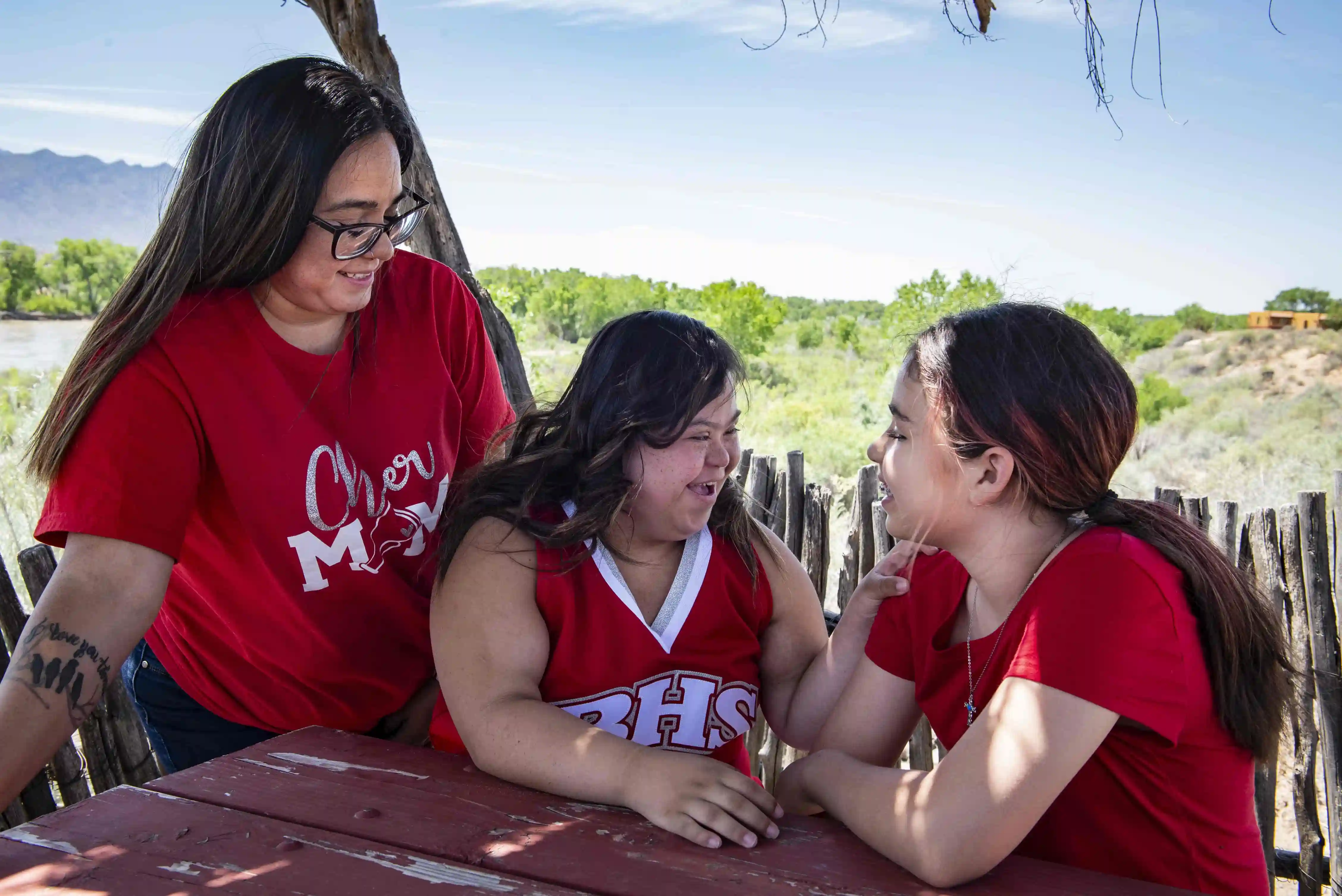 A young woman in a cheerleading outfit with two family members at her side