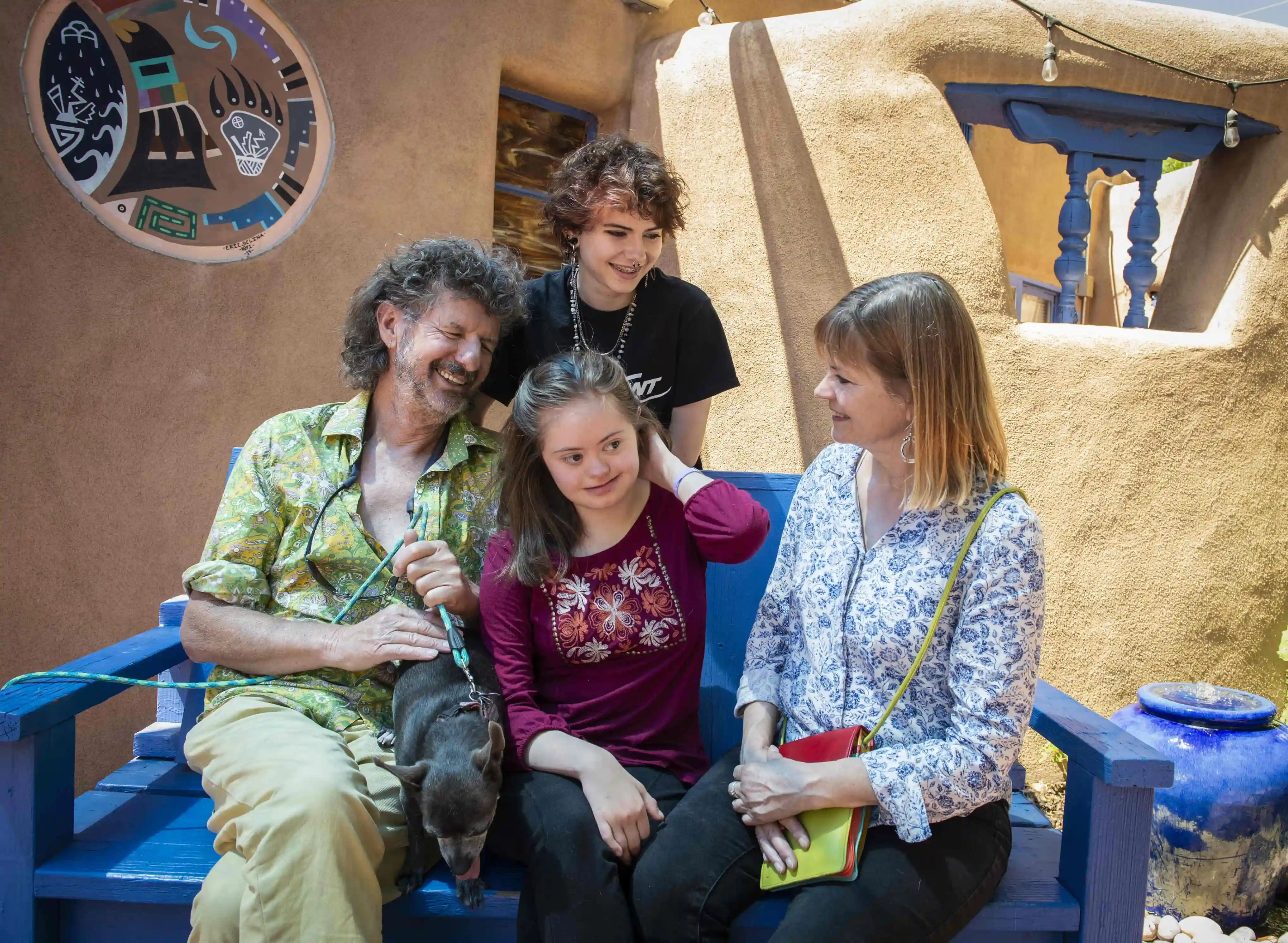 A family of four laughing as they relax on a bench